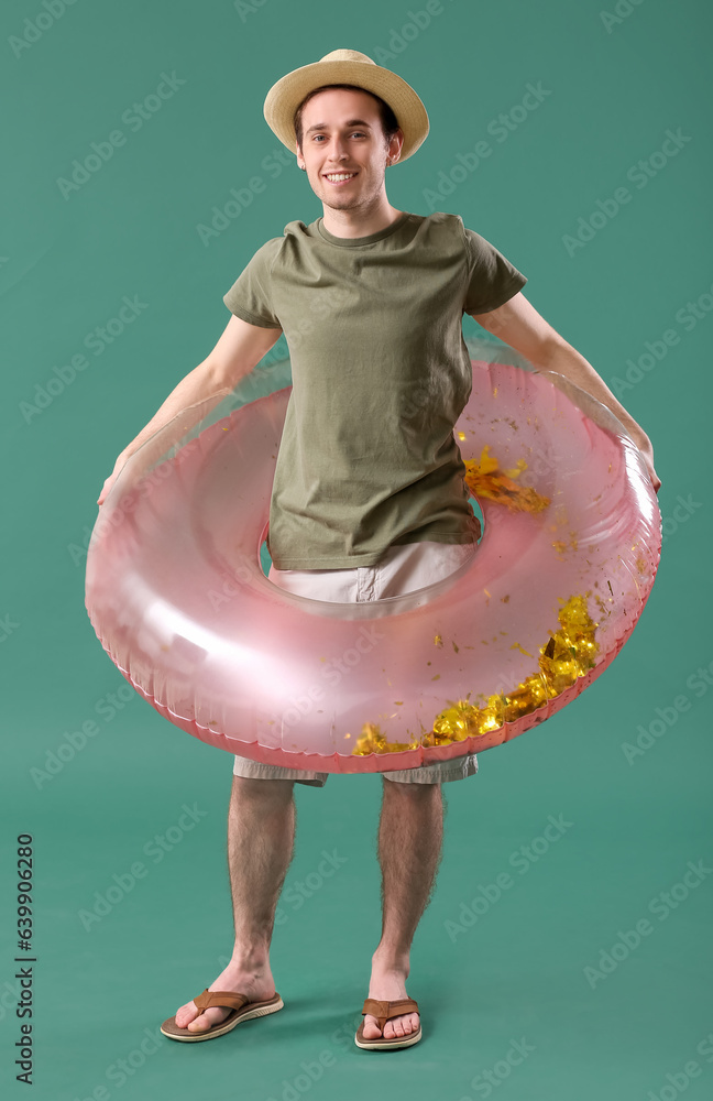 Young man with inflatable ring on green background