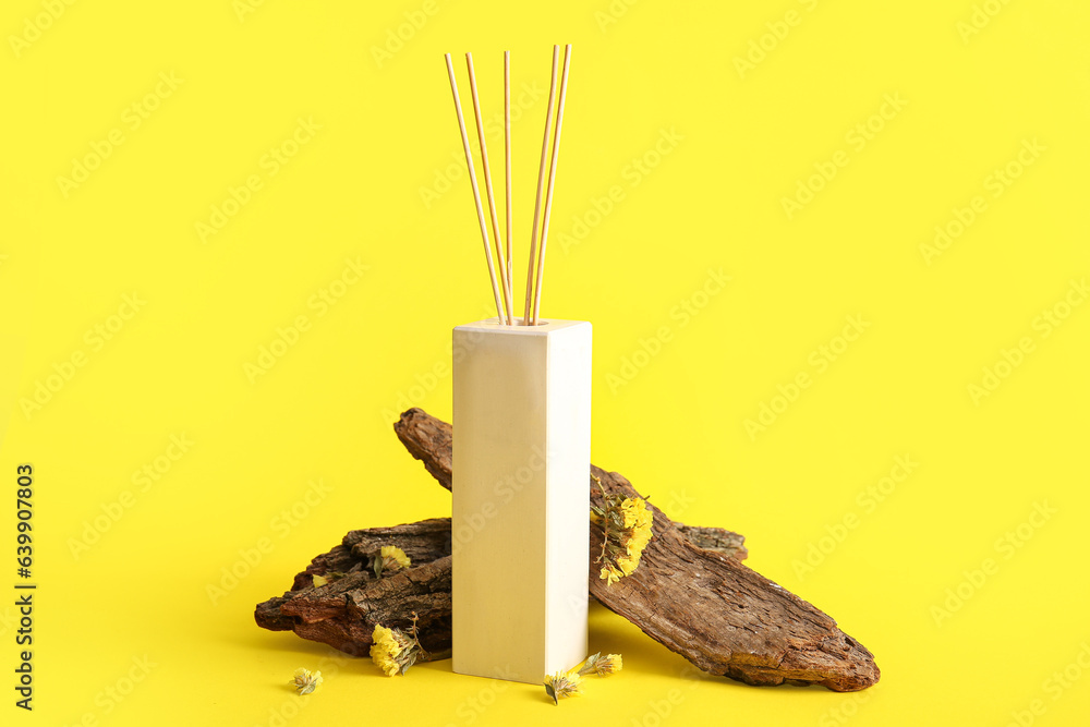 Reed diffuser and tree bark on yellow background