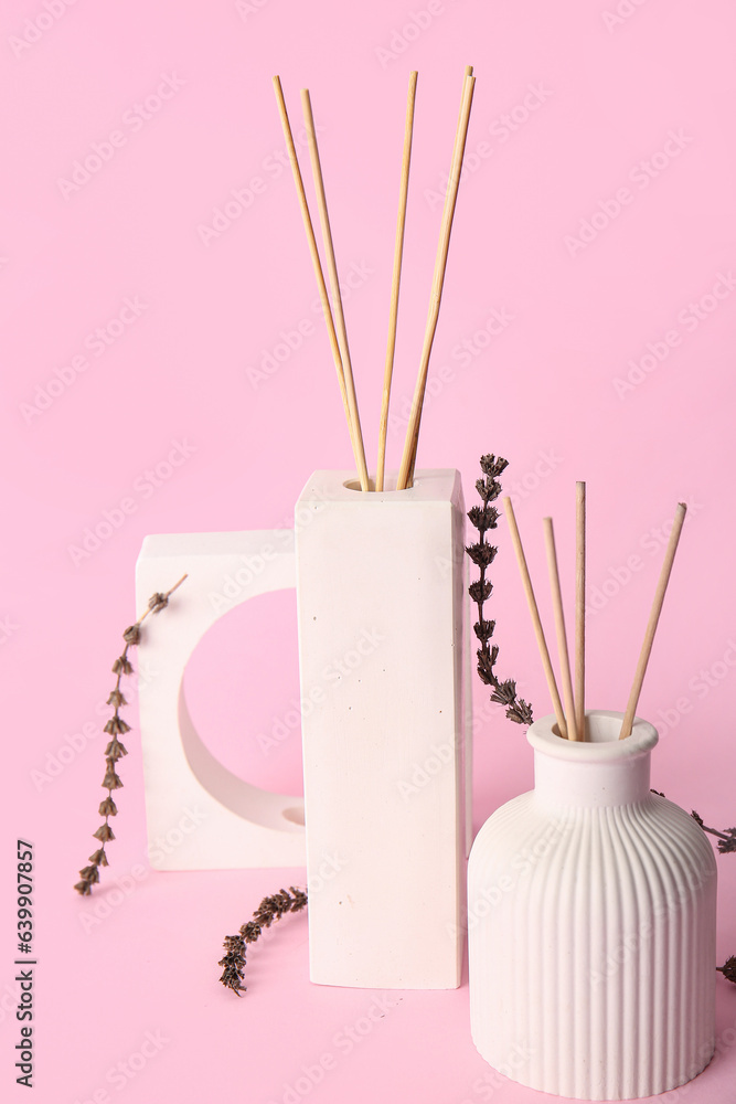 Bottles of floral reed diffuser on pink background