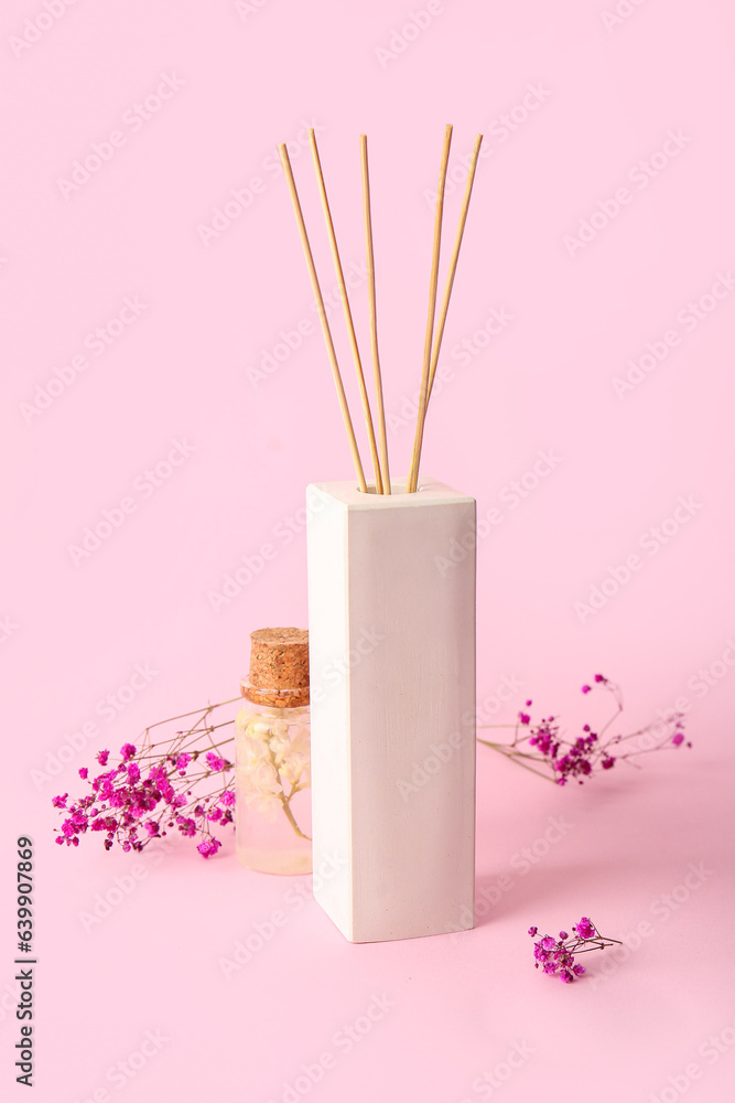 Floral reed diffuser and gypsophila flowers on pink background