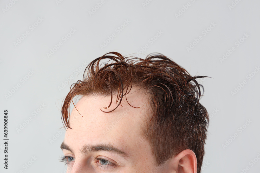 Young man with wet hair on light background