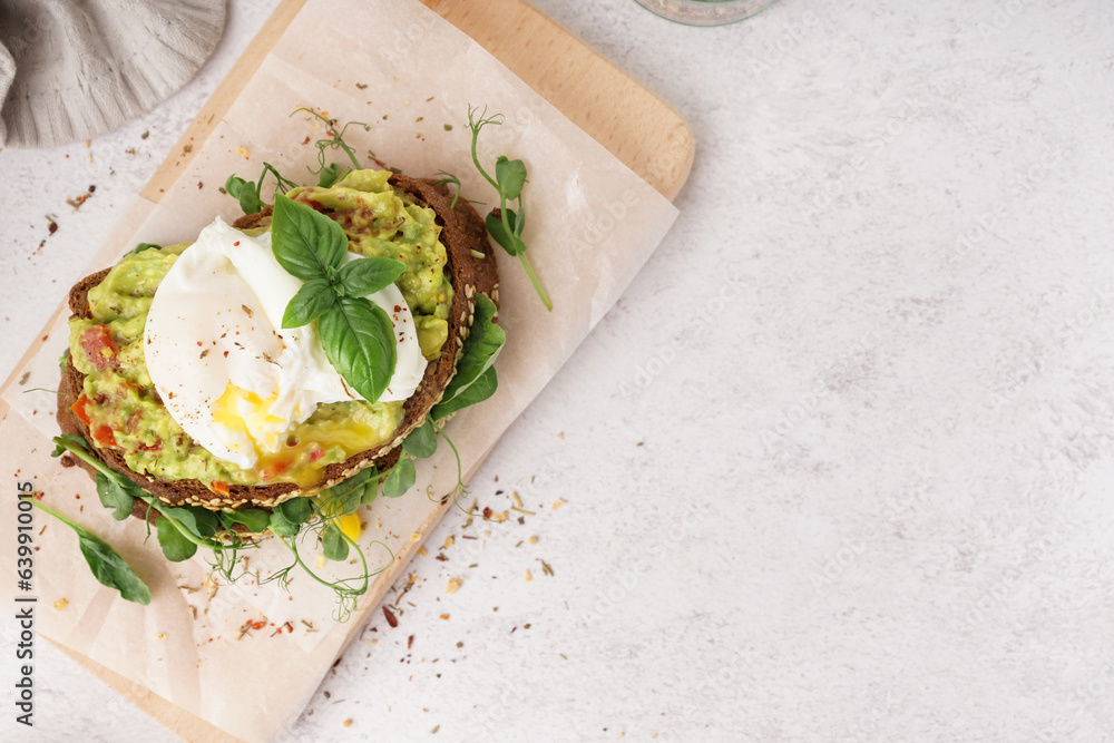 Wooden board of tasty sandwich with egg on light background