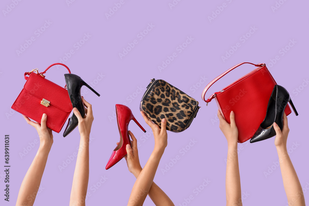 Female hands holding different stylish bags and high heels on lilac background