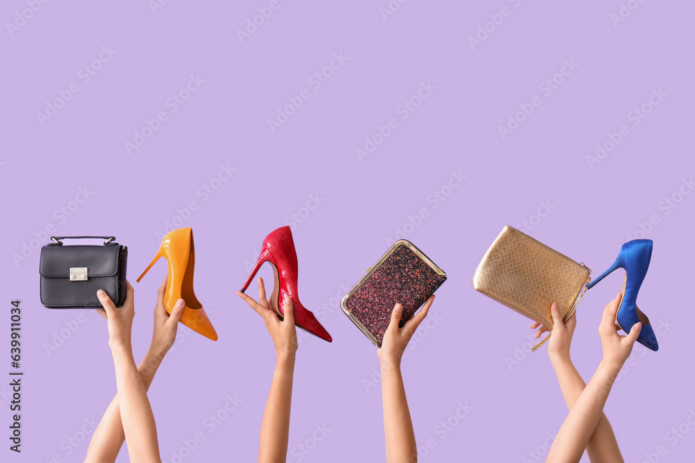 Female hands holding different stylish bags and high heels on lilac background