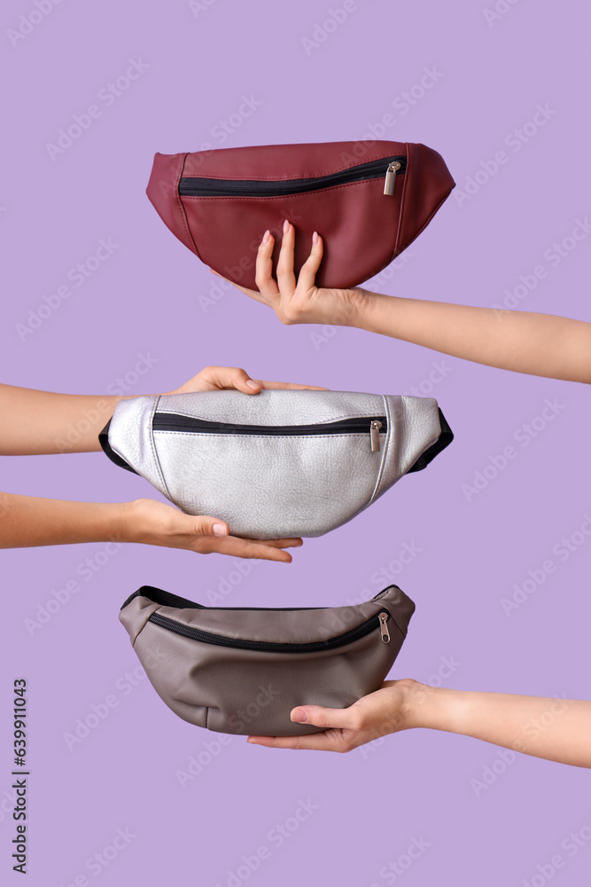 Female hands holding different stylish bags on lilac background