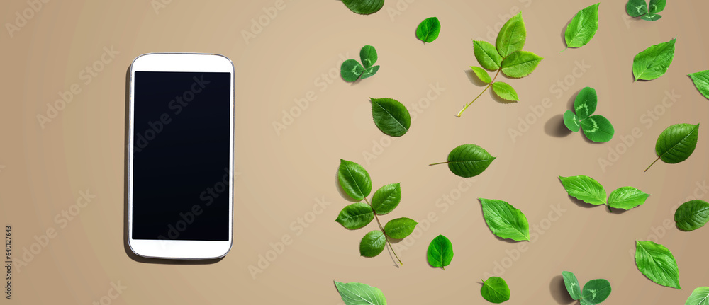 White smartphone with green leaves - flat lay