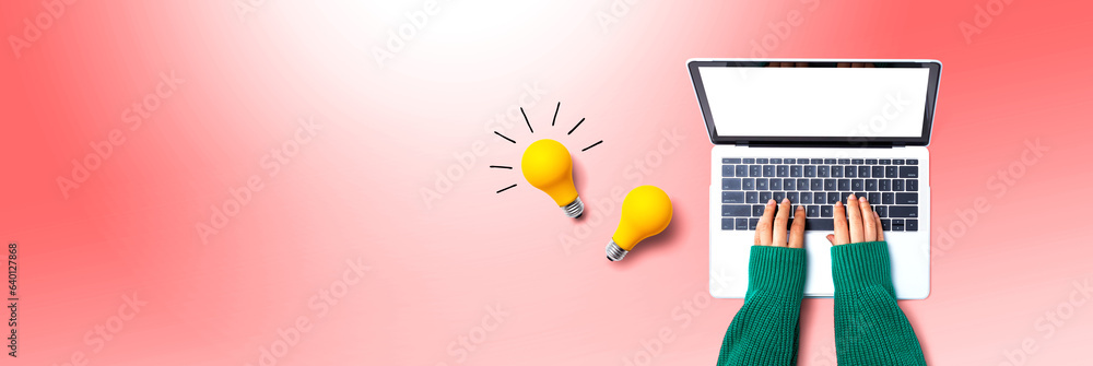 Person using a laptop computer and light bulbs - Flat lay