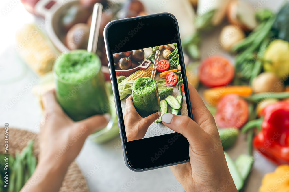 Woman taking a photo of a smoothie on her smartphone, close up.