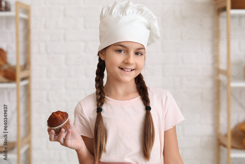 Little baker with tasty cupcake in kitchen