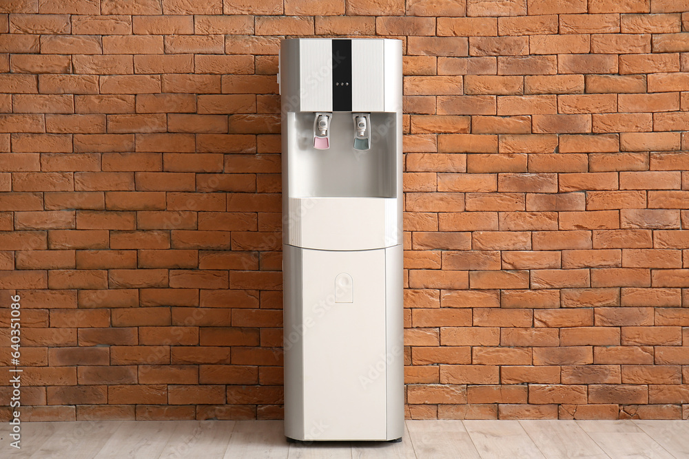 Modern water cooler near brick wall