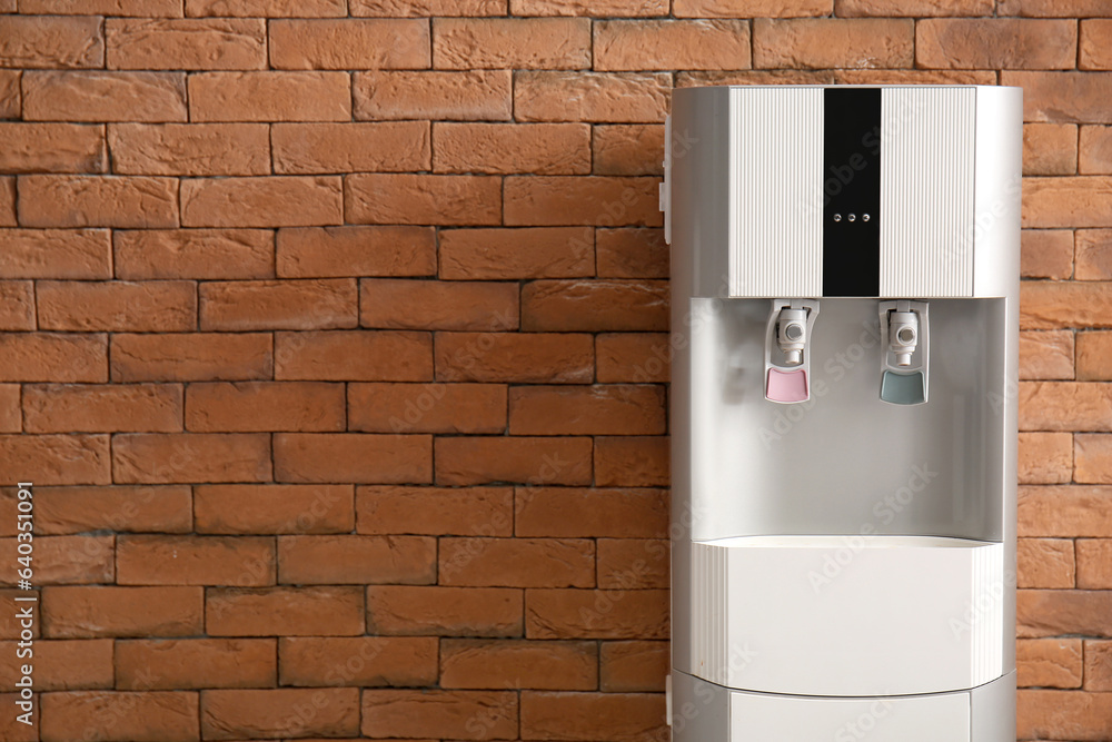 Modern water cooler on brick background