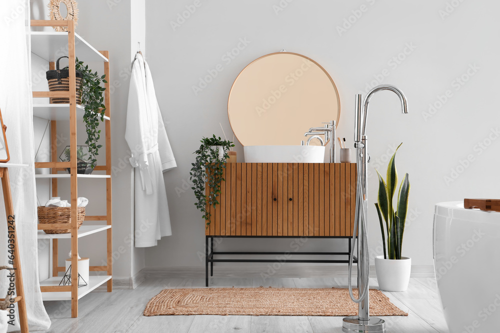 Wooden cabinet with sink bowl, faucet and mirror in interior of bathroom