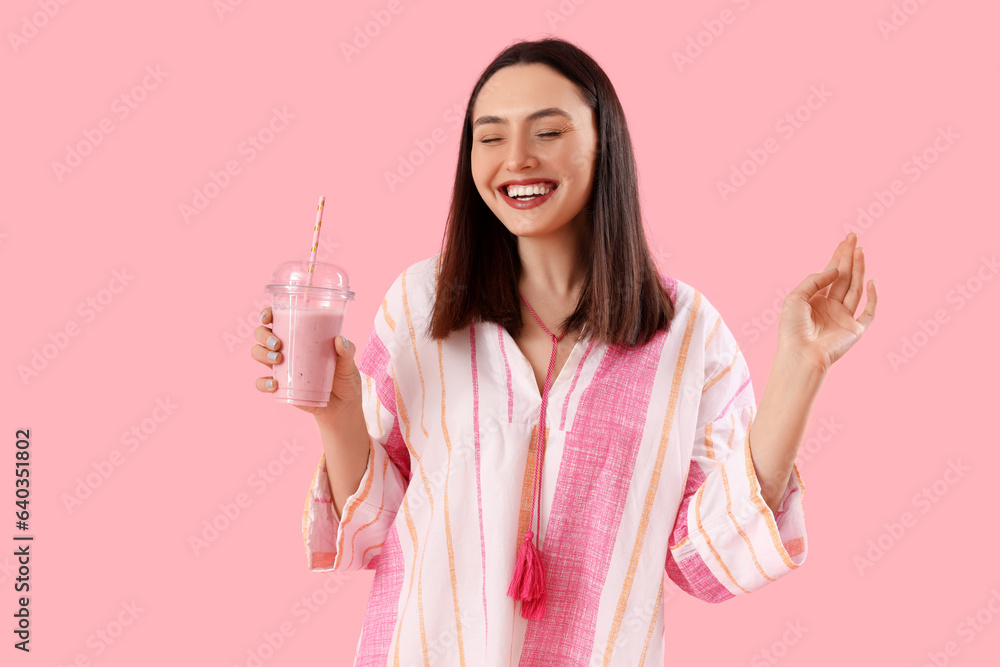 Young woman with glass of smoothie on pink background