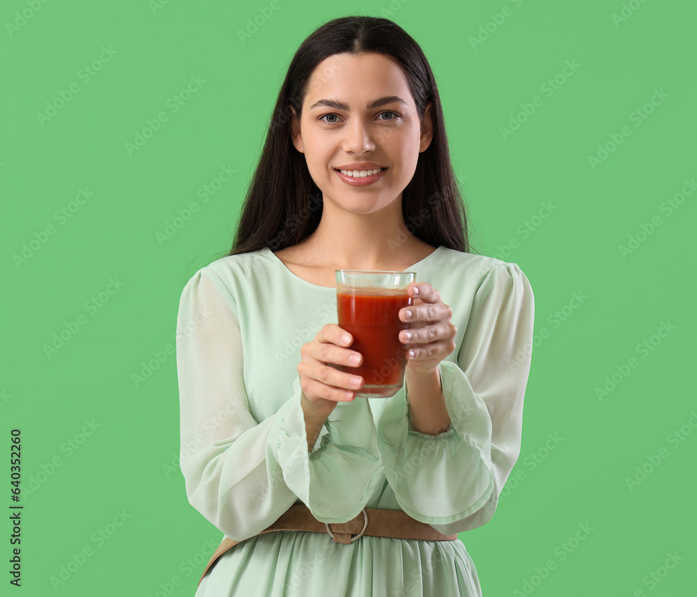 Young woman with glass of vegetable juice on green background