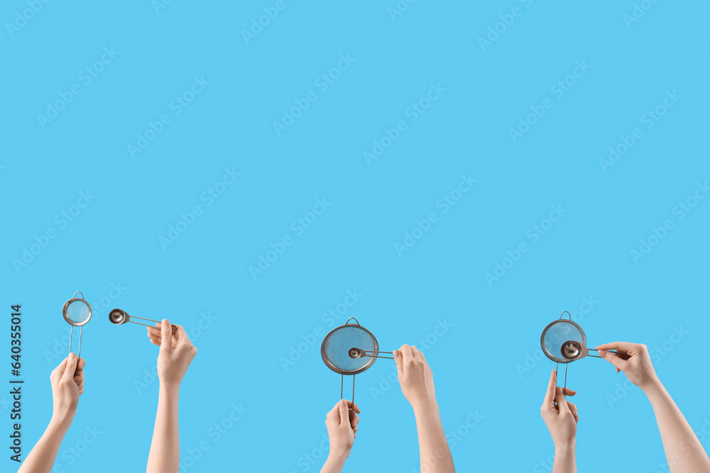 Female hands holding sieves and tea infusers on blue background