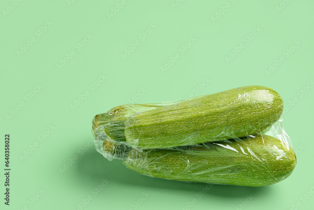 Fresh zucchini wrapped in stretch wrap on color background