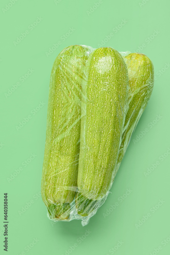 Fresh zucchini wrapped in stretch wrap on color background