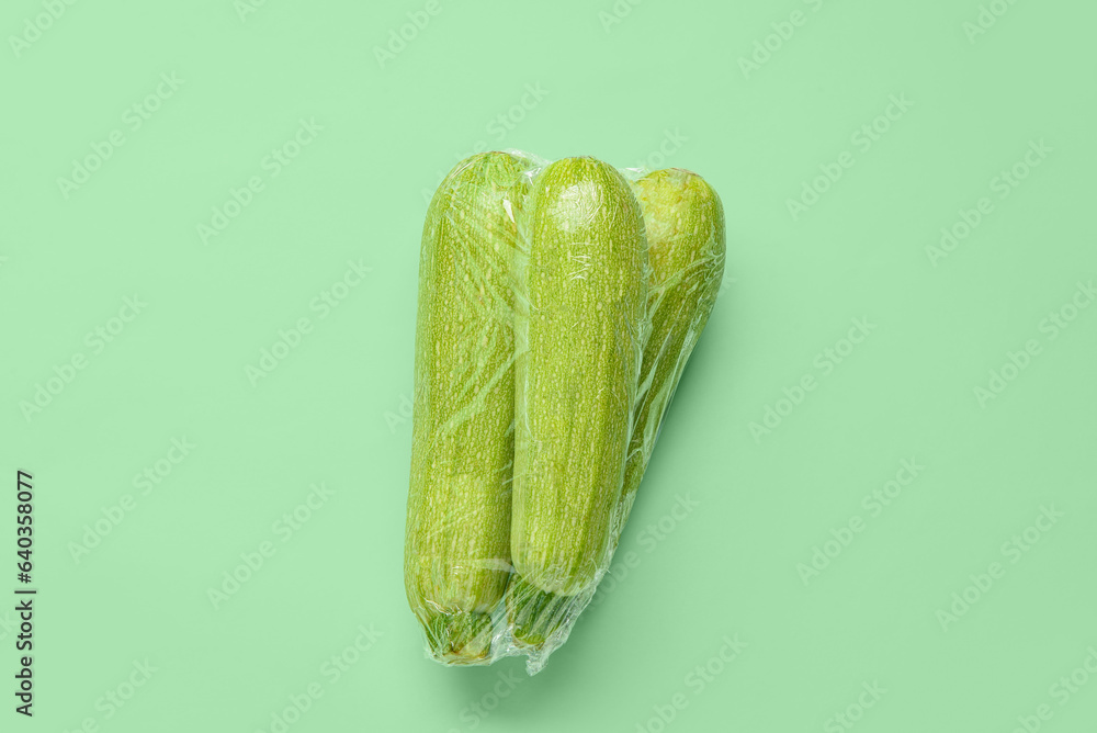 Fresh zucchini wrapped in stretch wrap on color background