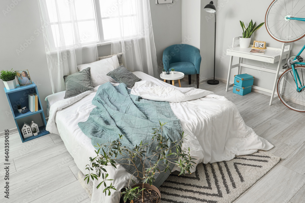 Interior of light childrens bedroom with cozy bed, houseplants and bicycle