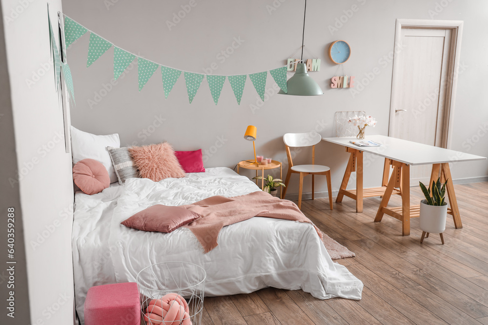 Interior of childrens bedroom with cozy bed, table and garland