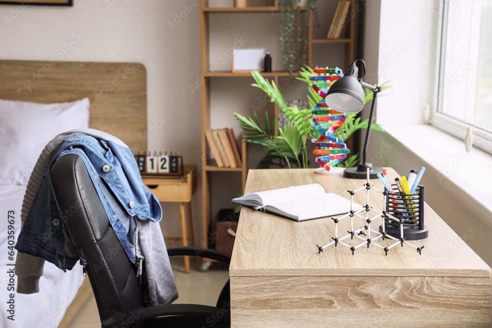 Wooden desk with molecule and DNA models in interior of childrens bedroom