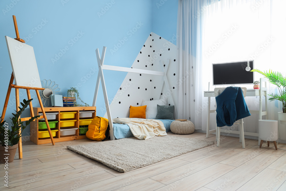 Interior of childrens bedroom with cozy bed, easel and modern computer on desk