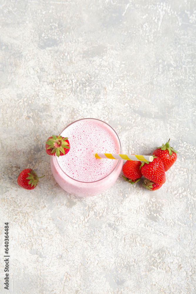 Glass of tasty strawberry smoothie on light background