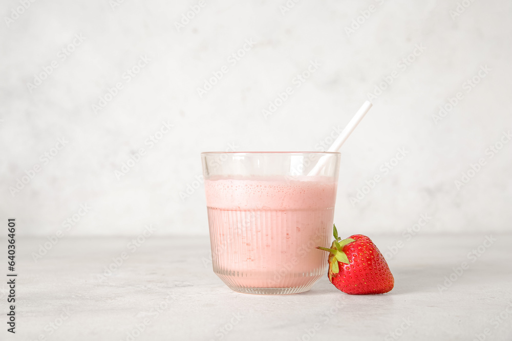 Glass of tasty strawberry smoothie on light background