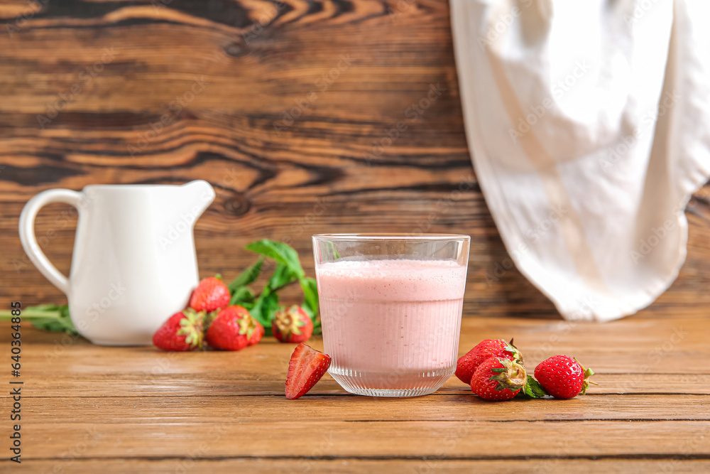 Glass of tasty strawberry smoothie on wooden background