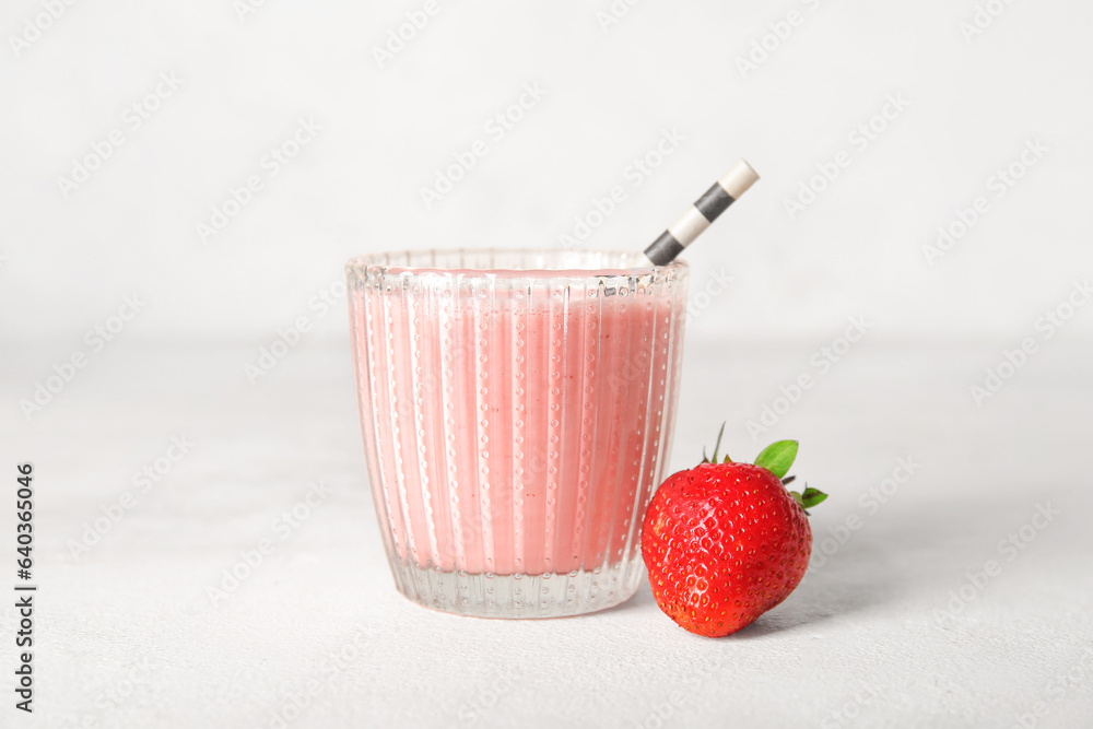 Glass of tasty strawberry smoothie on light background