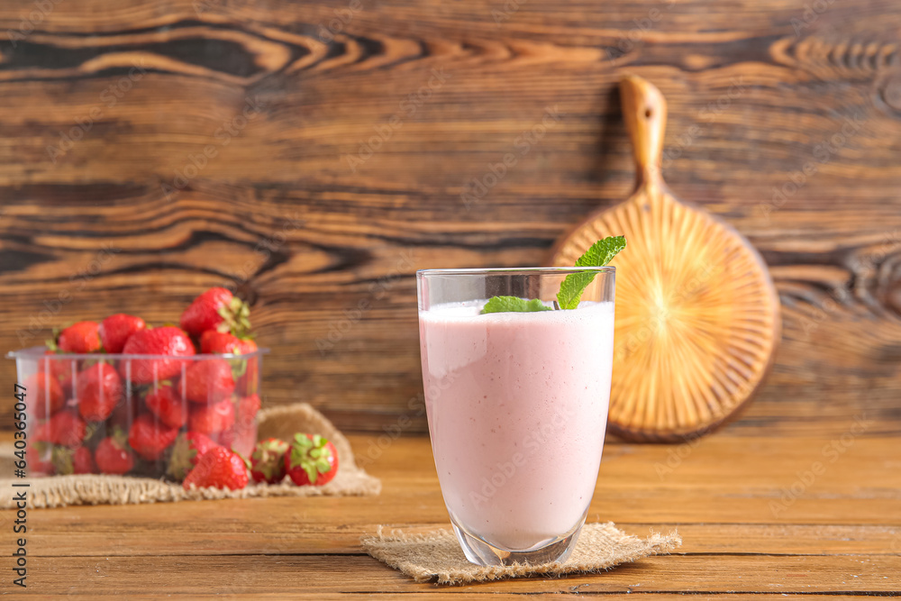 Glass of tasty strawberry smoothie on wooden background