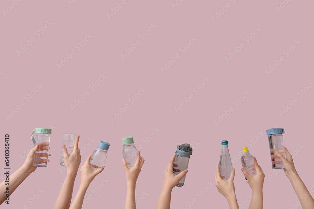 Female hands with bottles and glass of cold water on pink background