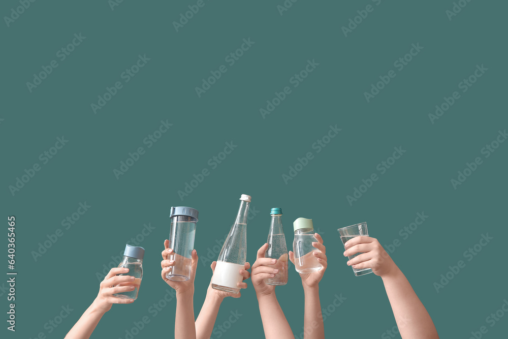 Female hands with bottles and glass of cold water on green background