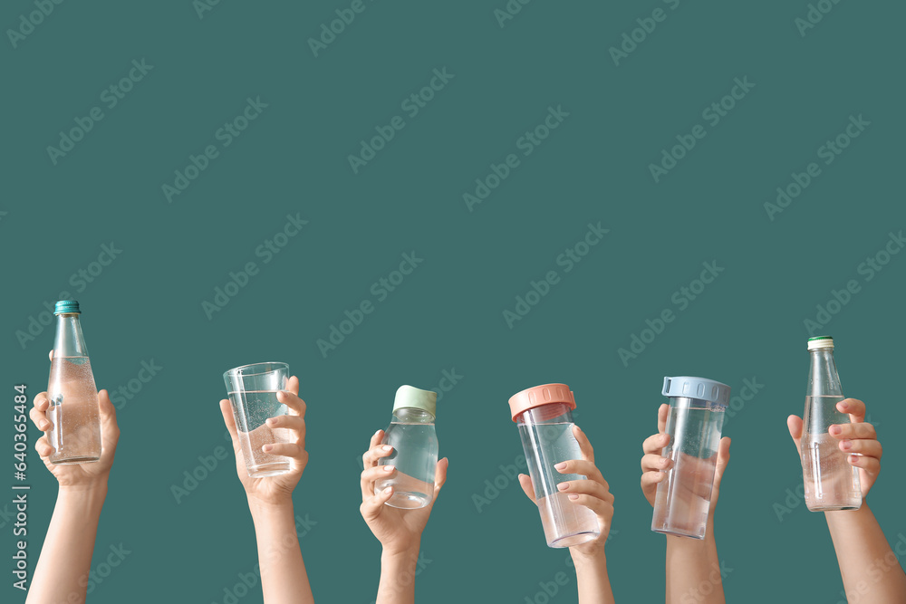 Female hands with bottles and glass of cold water on green background