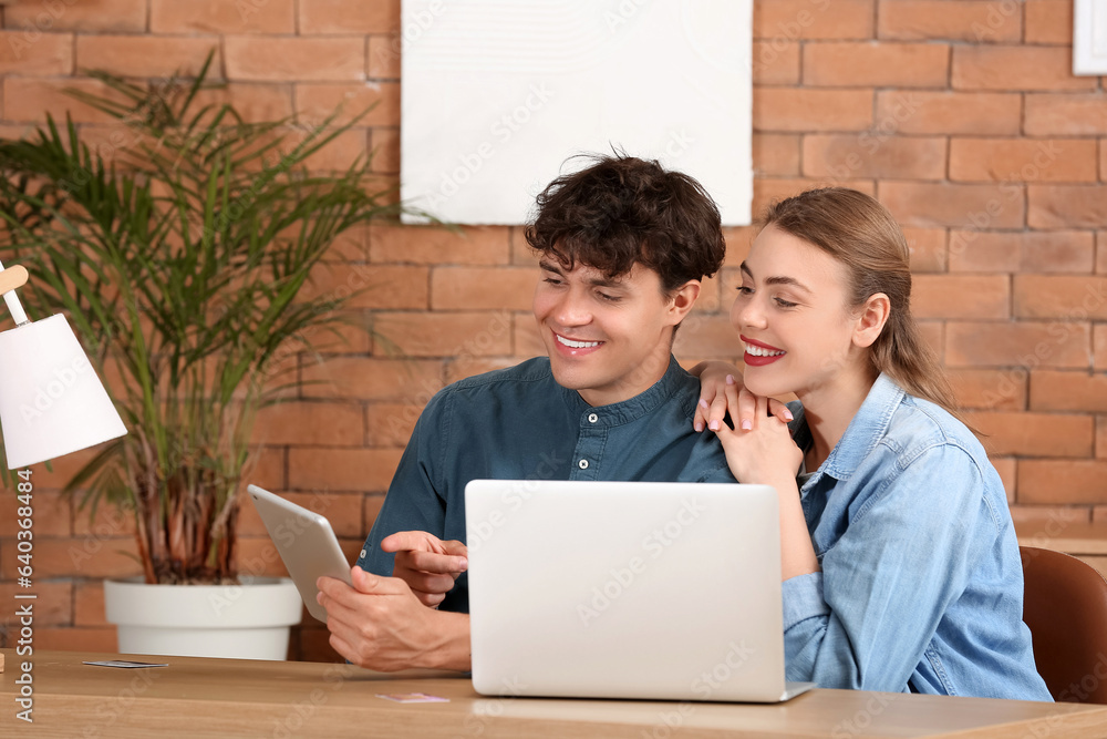 Young couple with tablet computer shopping online at home