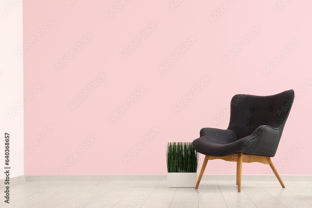 Grey armchair and houseplant near pink wall