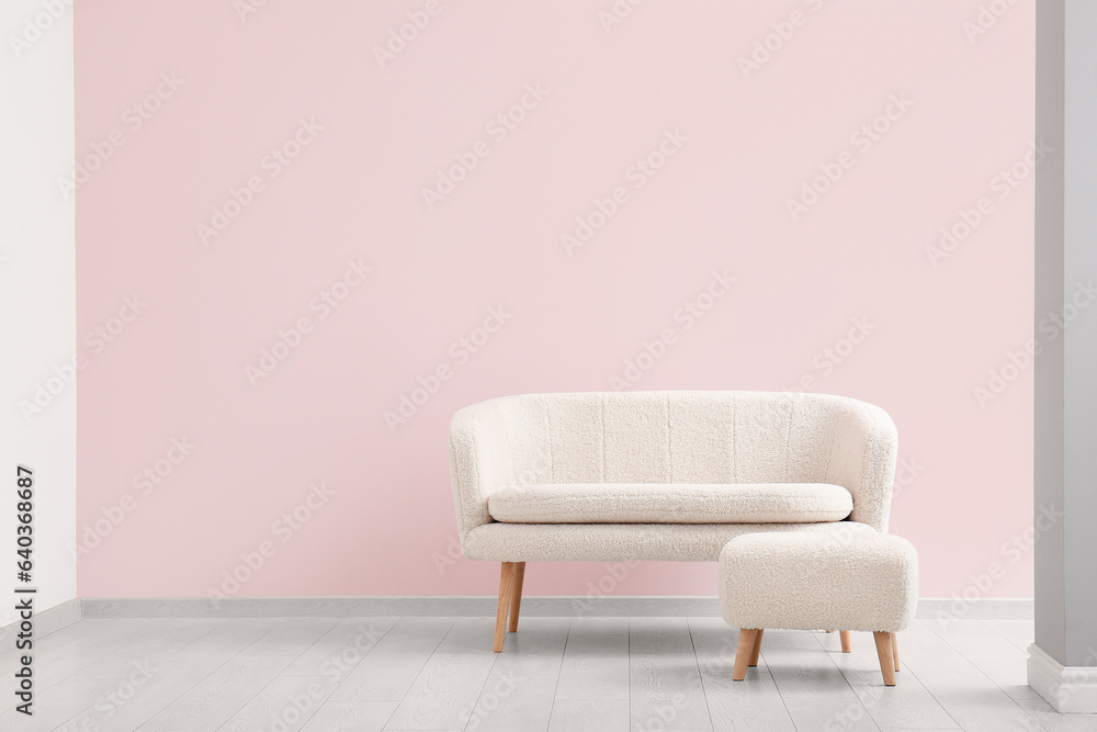 Cozy white sofa and pouf near pink wall