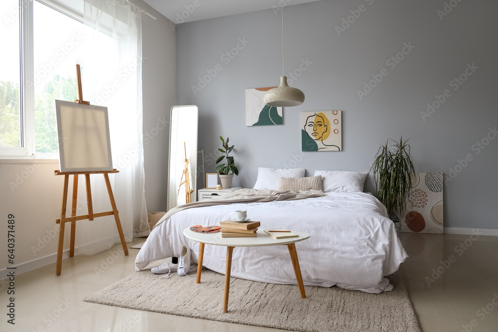 Interior of light childrens bedroom with easel and cozy bed