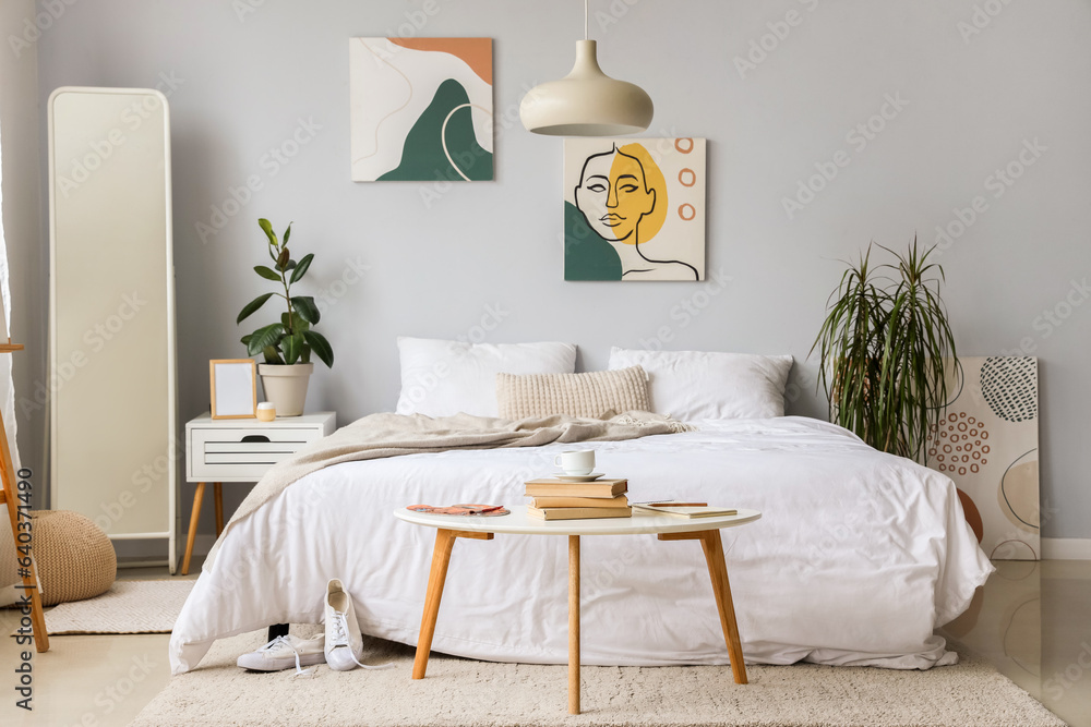 Interior of childrens bedroom with cozy bed, palette, books and cup on table