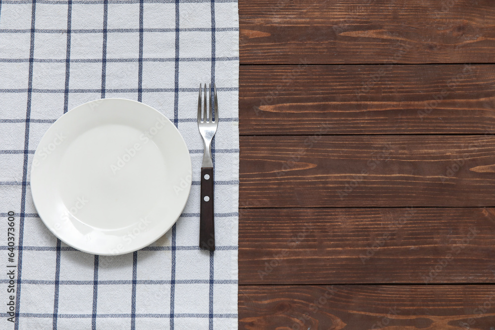 Clean plate, fork and napkin on wooden background