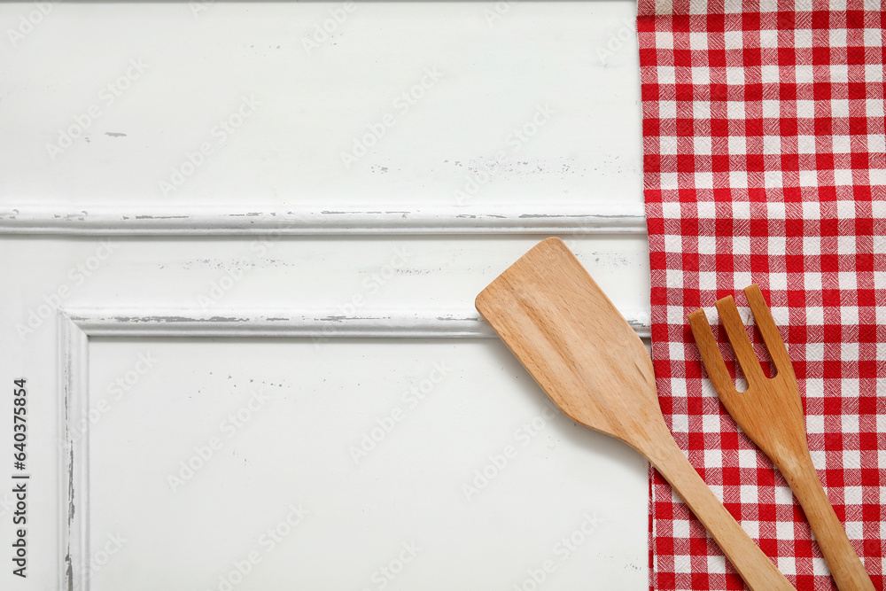 Spatula, fork and napkin on white wooden background