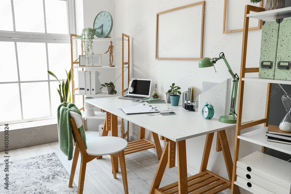 Interior of light office with workplace and shelving units