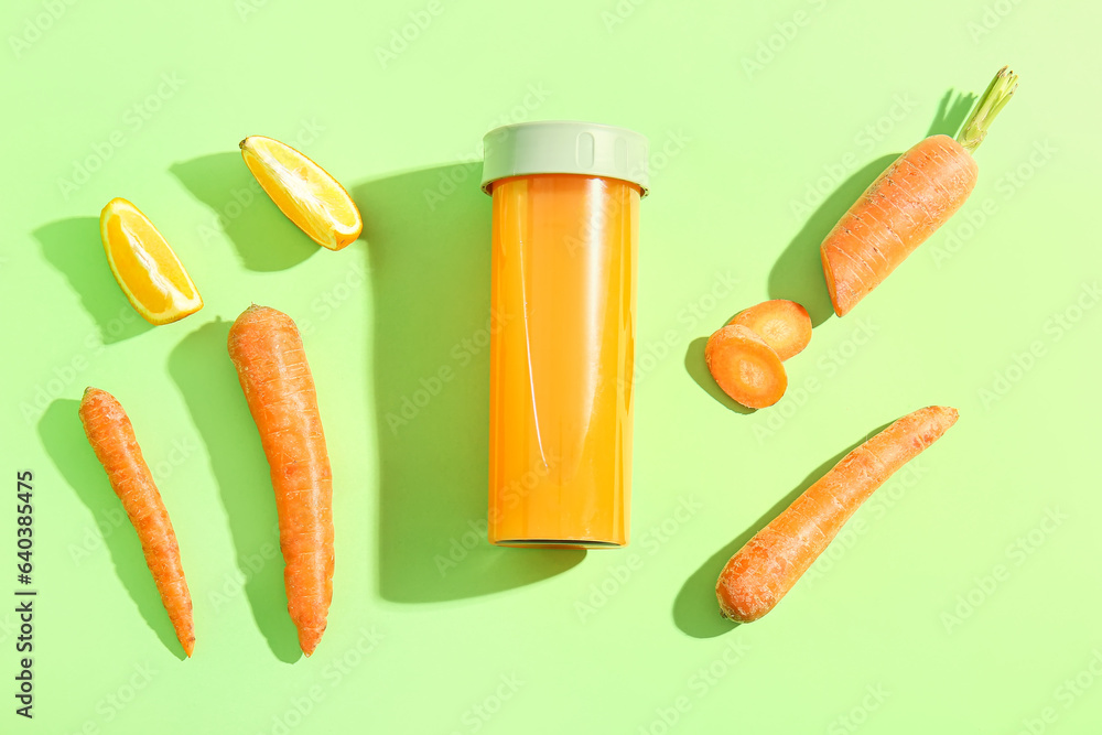 Sports bottle of fresh carrot juice with orange on green background