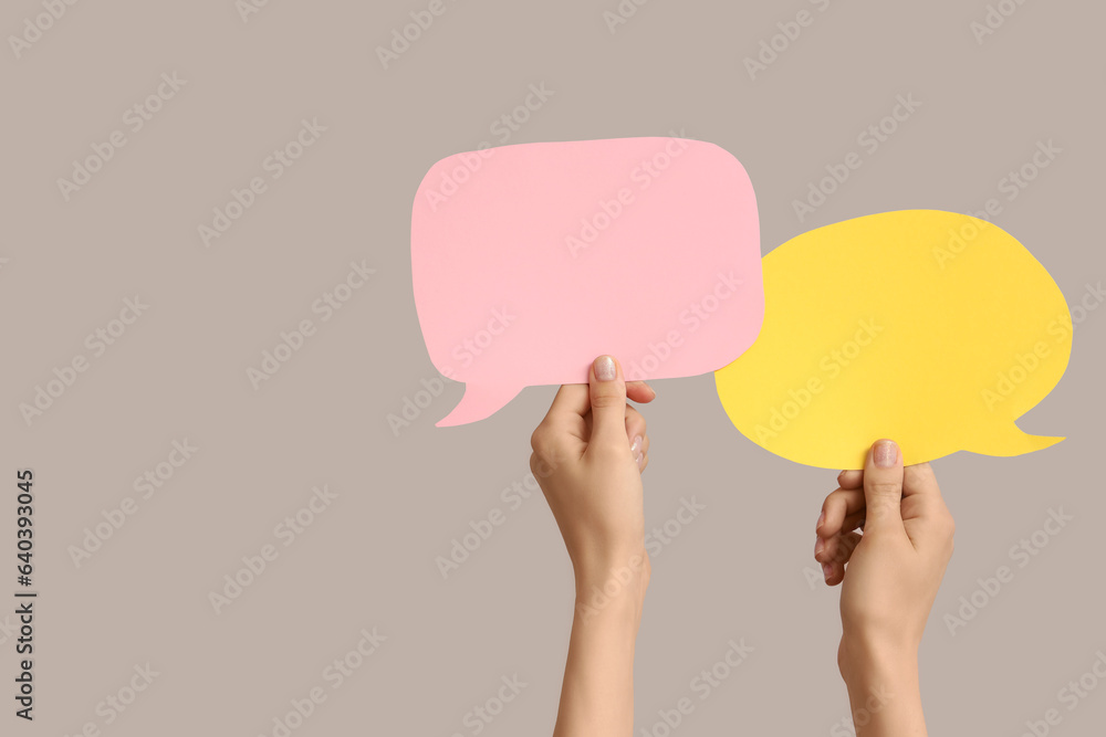 Female hands with speech bubbles on grey background