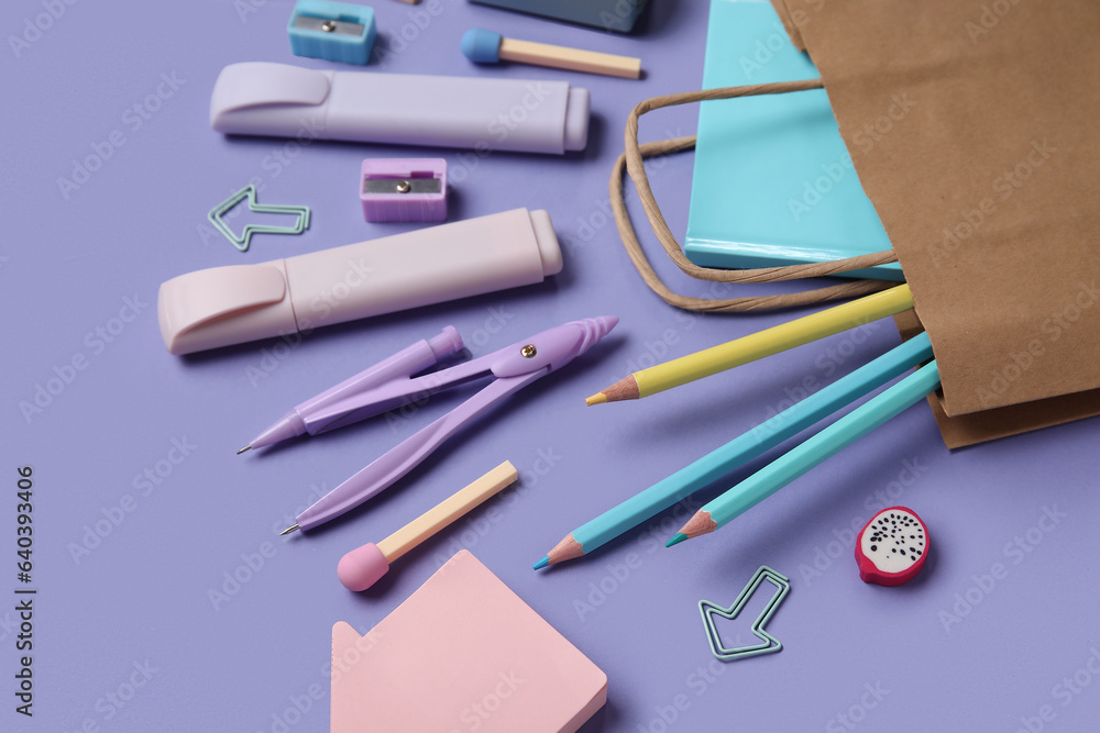 Shopping bag with different school stationery on purple background, closeup