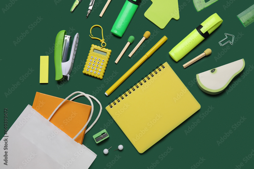 Shopping bag with different school stationery on green background