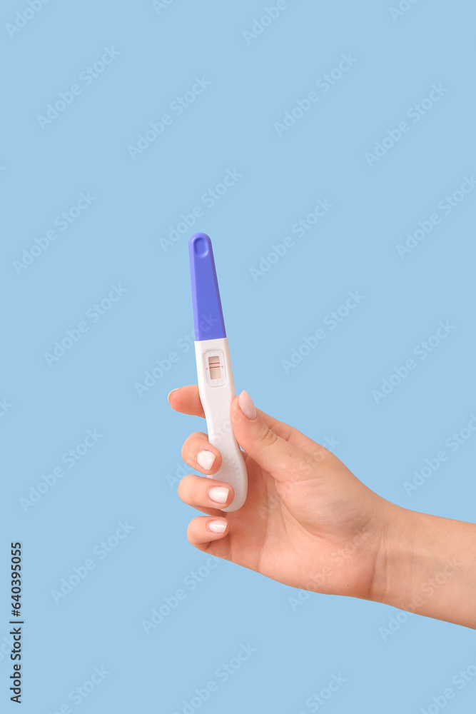 Female hand with positive pregnancy test on color background