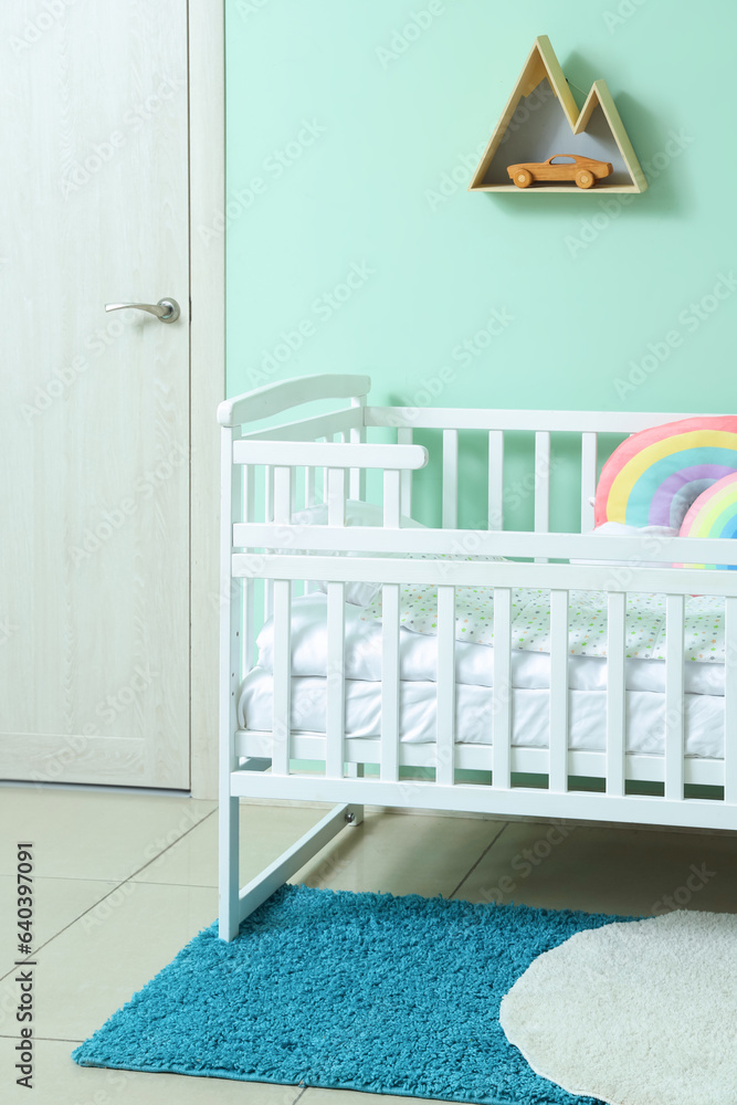 Interior of childrens room with crib near turquoise wall