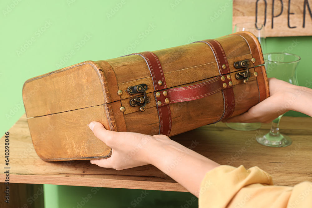 Woman putting suitcase on wooden shelf, closeup