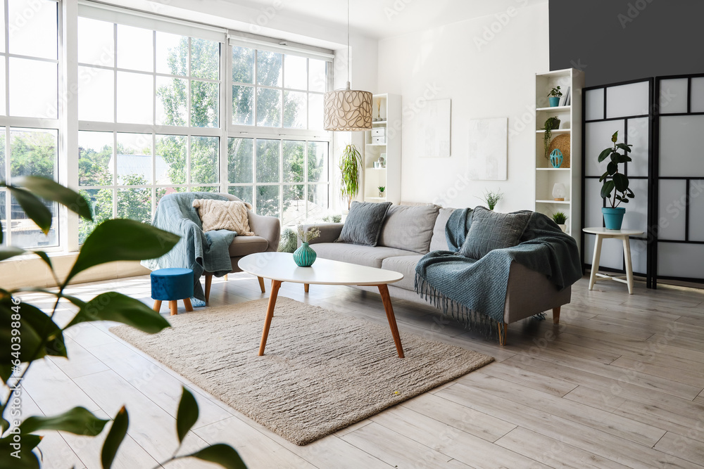 Interior of light living room with armchair, grey sofa and coffee table